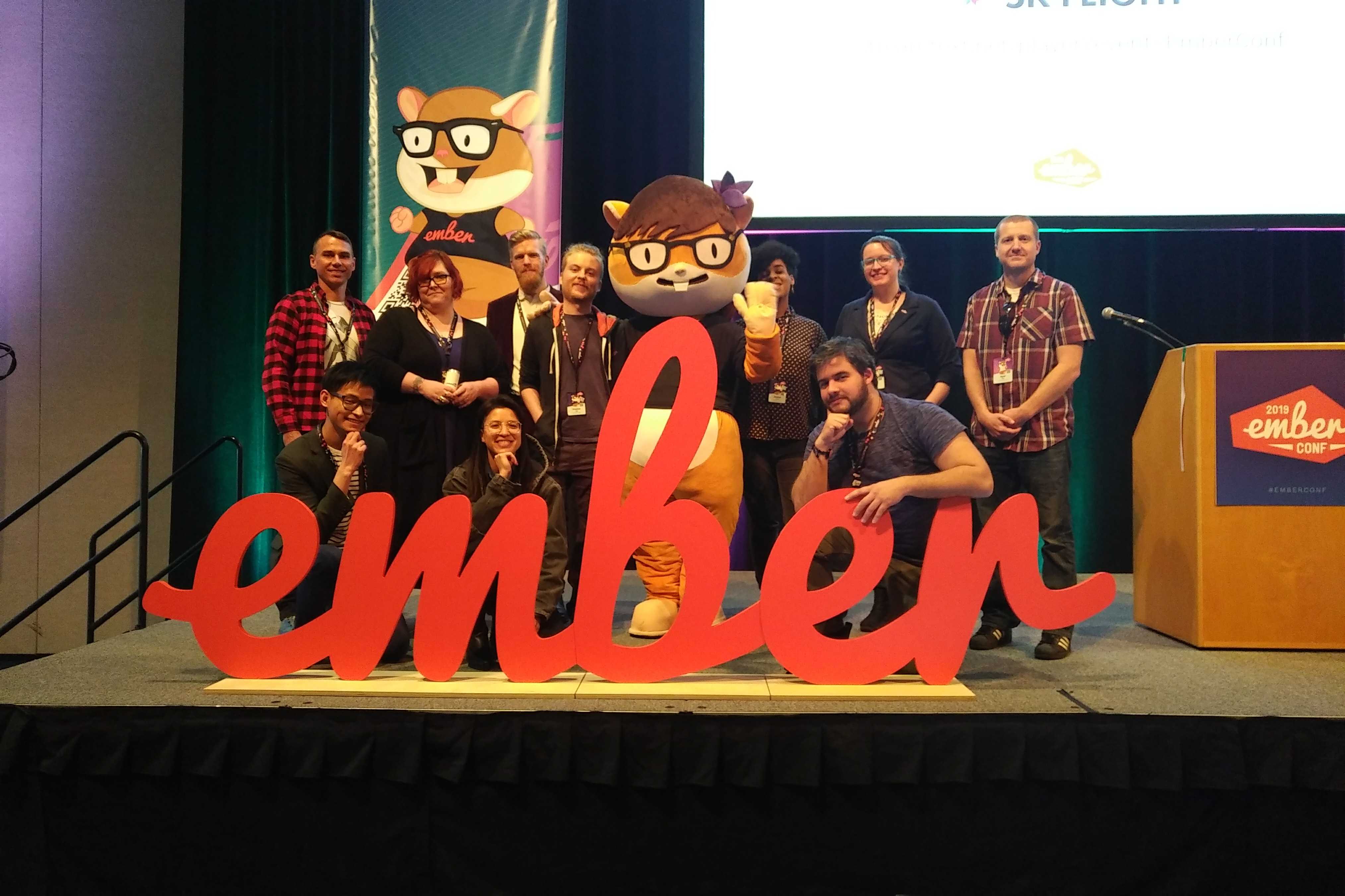 The Ember Times Team 2019 and the Zoey mascot posing on stage behind the Ember logo and looking cool as ever 😎